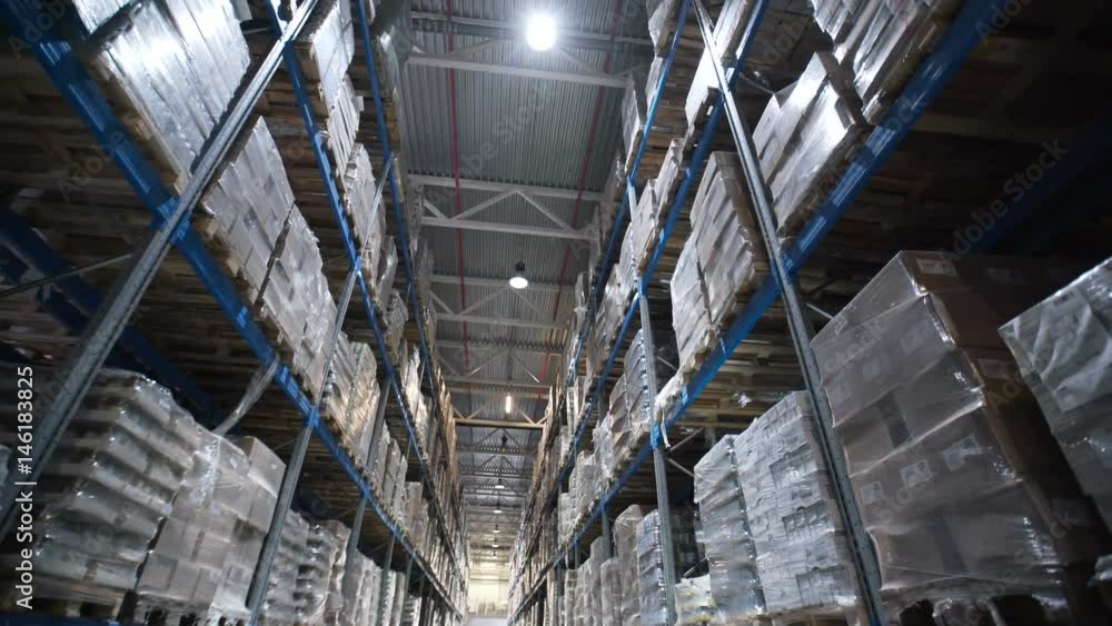Large warehouse logistics terminal. Camera moves up on shelves of cardboard boxes inside a storage warehouse. Industrial warehouse with boxes Large warehouse logistics terminal. Camera moves up on shelves of cardboard boxes inside a storage warehouse. Industrial warehouse with boxes
