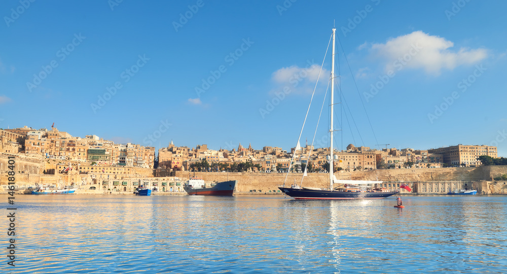 Sailing ship enters Grand Valetta bay on a bright day, panorama