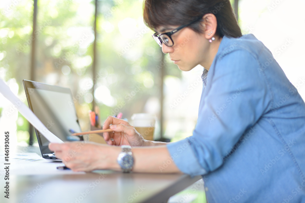 Businesswoman working in office with laptop computer and documents Businesswoman working in office with laptop computer and documents