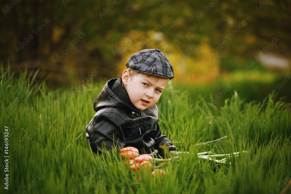 The boy on the lawn in spring with a bouquet of flowers . Spring gift . The boy on the lawn in spring with a bouquet of flowers . Spring gift .