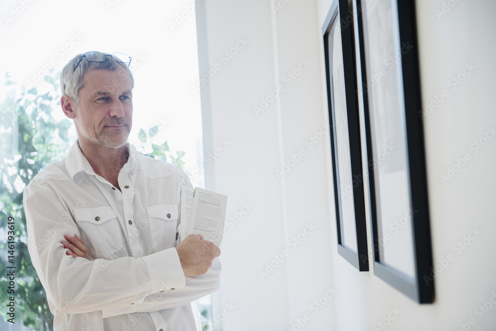 Older Caucasian man admiring artwork in gallery Older Caucasian man admiring artwork in gallery