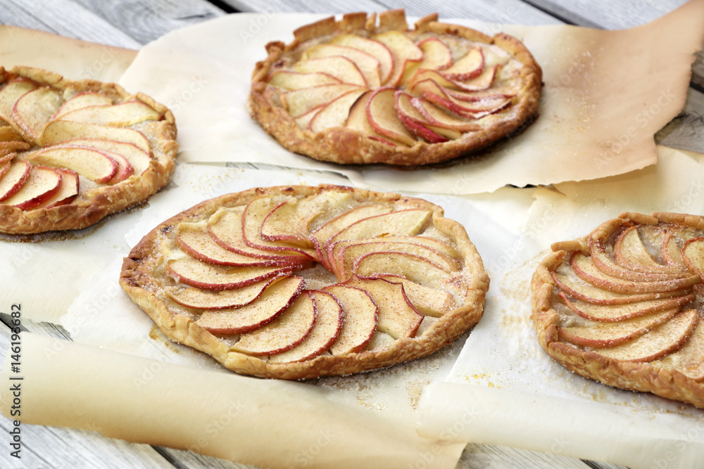 Apple pie on the thin crust with sugar and cinnamon. Apple tart with ricotta cheese and cinnamon. Round pies on the white wooden background. Apple's slices. Piece of pie.