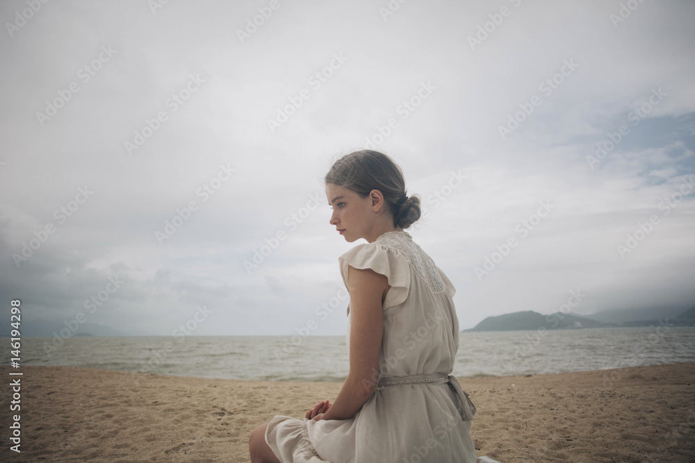 Caucasian women wearing dress sitting on beach Caucasian women wearing dress sitting on beach