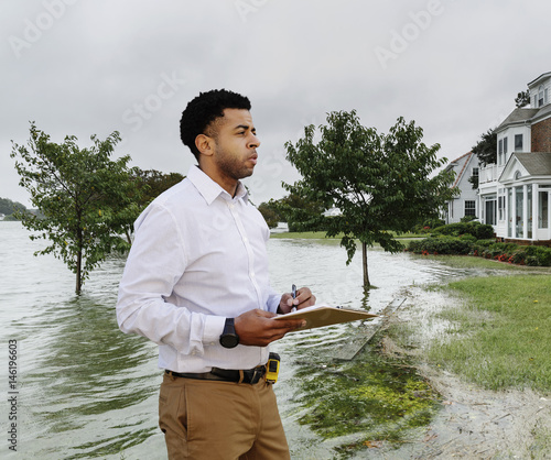 Black insurance adjuster examining flooding damage to house