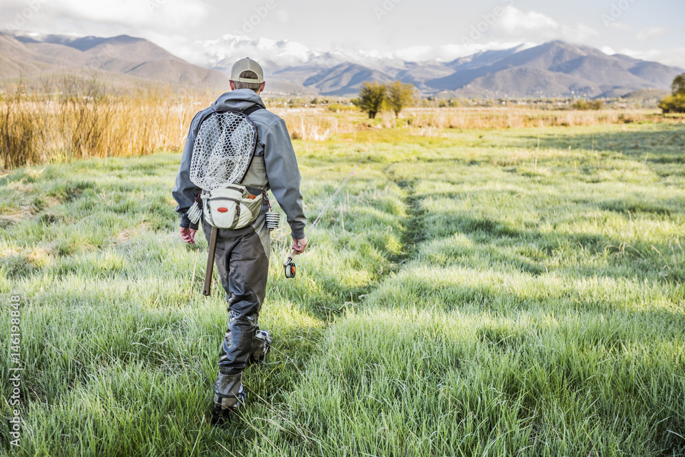 Caucasian man carrying fishing rod in field Caucasian man carrying fishing rod in field