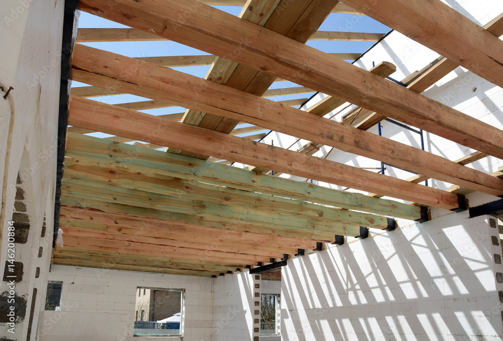 Obraz premium The wooden structure of the building. Wooden frame building. Wooden roof construction. photo for home. house building. Installation of wooden beams at construction the roof truss system of the house.