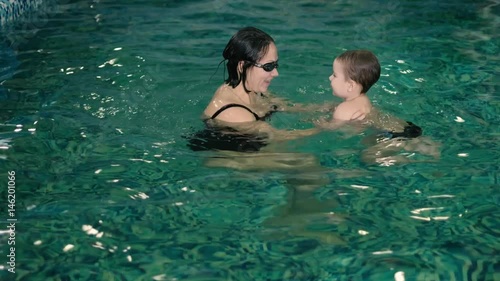 Happy mother teaching to son in swimming pool 4k