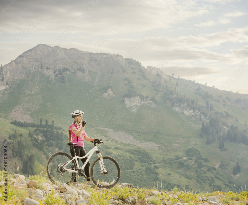 Caucasian woman with mountain bike drinking from backpack Caucasian woman with mountain bike drinking from backpack
