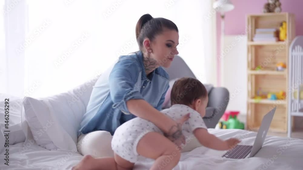 Multi tasking mother with baby son working at home Multi tasking mother with baby son working at home