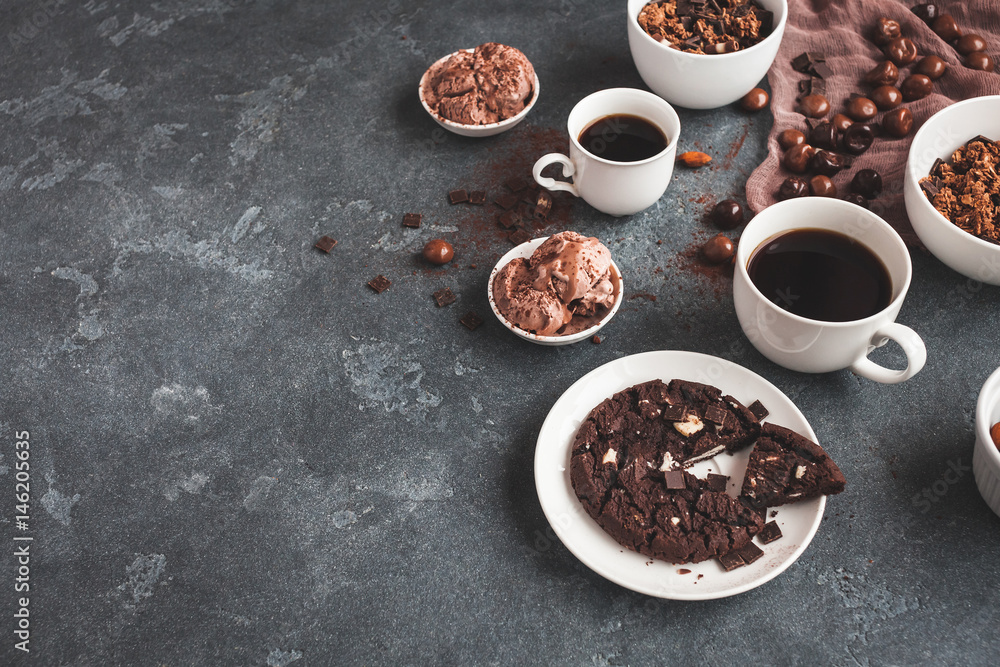 Chocolate cake, cups of coffee, chocolate muesli and chocolate ice cream on dark background Chocolate cake, cups of coffee, chocolate muesli and chocolate ice cream on dark background