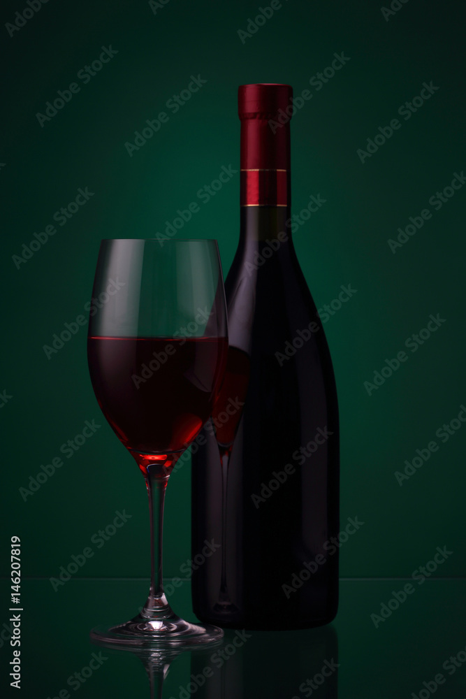 Bottle of red wine and glass on green Bottle of red wine and glass on green