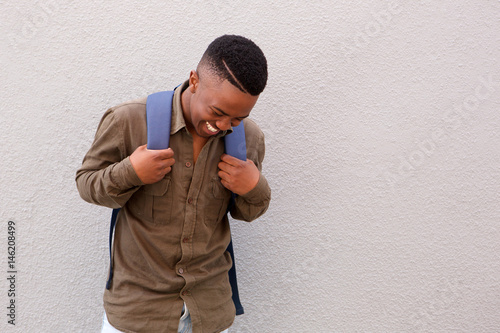 happy black male student laughing with bag © mimagephotos