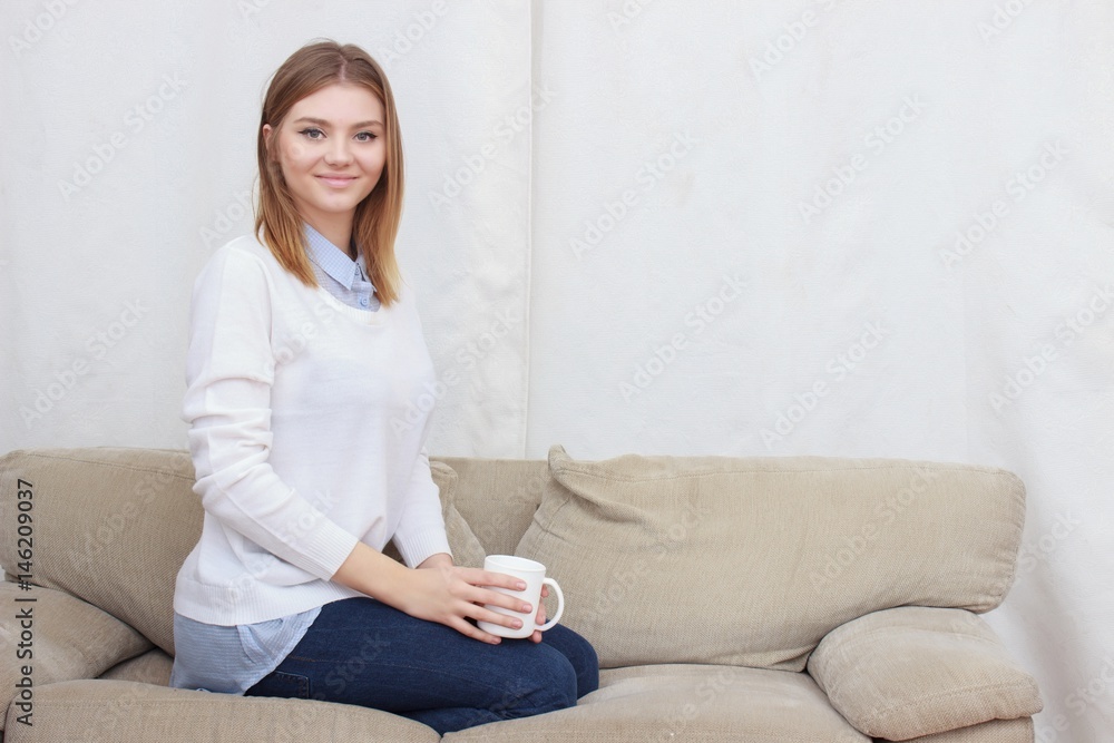woman sitting on couch in her living room and drinking coffee woman sitting on couch in her living room and drinking coffee