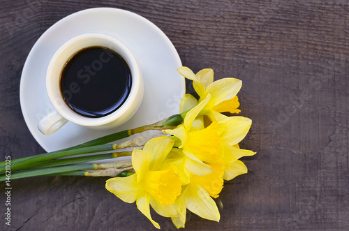 Fototapeta Naklejka Na Ścianę i Meble -  Coffee cup and bouquet of narcissus flowers on old rustic wooden table.Coffee mug and spring flowers.Spring morning,Breakfast,Good morning concept.