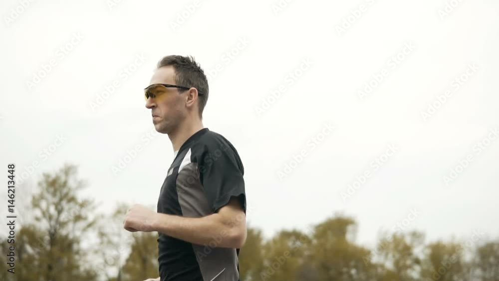 Young attractive man wears yellow sunglasses, running at the stadium, jogging style Young attractive man wears yellow sunglasses, running at the stadium, jogging style