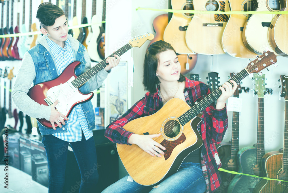 Obraz premium Teenagers examining both electric and acoustic guitars