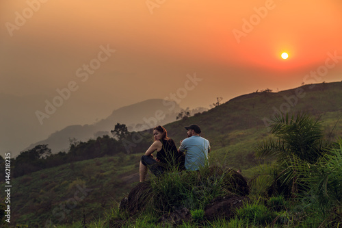 Tourists watching the sunset on top of the mountain.
