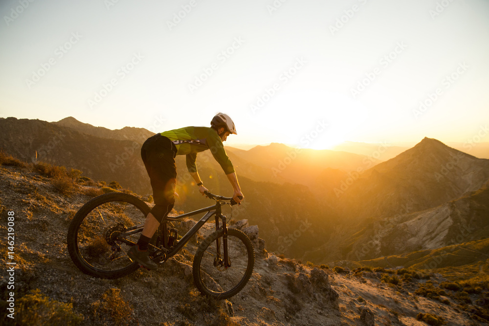 Obraz premium Cyclist man riding mountain bike at sunset