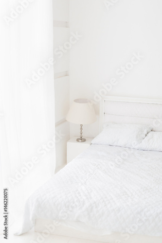 Total white room interior with bed, lamp, window with curtain