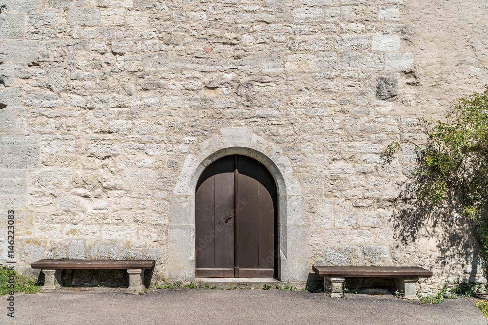 Alte Burgmauer mit Holztüre und zwei Holzbänken Alte Burgmauer mit Holztüre und zwei Holzbänken
