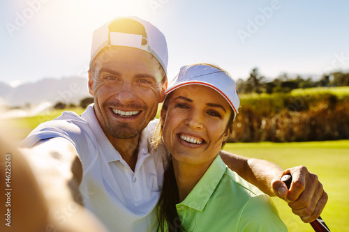 Happy young couple taking selfie at golf course