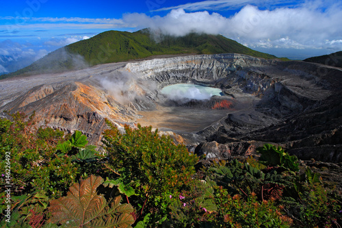 Poas volcano in Costa Rica. Volcano landscape from Costa Rica. Active volcano with blue sky with clouds. Hot lake in the crater Poas. Volcano in Costa Rica. The crater and the lake of the hill Arenal.
