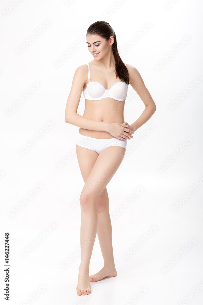 beautiful young brunette woman with perfect sporty body in white lingerie on white background. Full length portrait beautiful young brunette woman with perfect sporty body in white lingerie on white background. Full length portrait