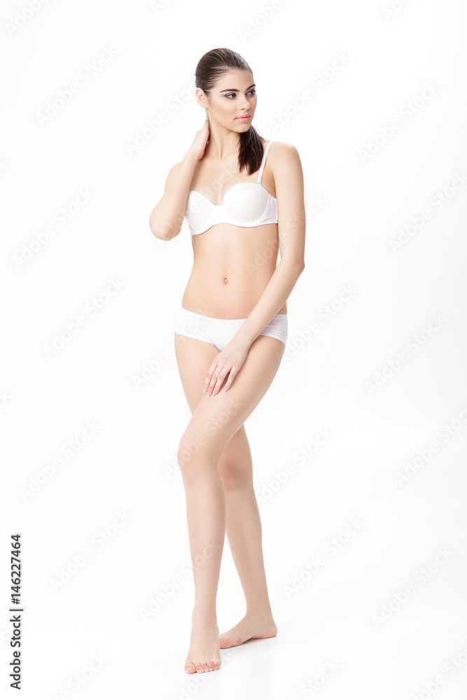 beautiful young brunette woman with perfect sporty body in white lingerie on white background. Full length portrait beautiful young brunette woman with perfect sporty body in white lingerie on white background. Full length portrait