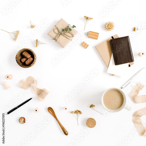 Blogger or freelancer workspace with coffee mug, notebook, sweets and accessories on white background. Flat lay, top view minimalistic brown styled home office desk. Brown styled composition