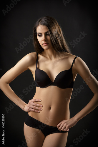 beautiful sexy brunette woman posing in black lingerie on black background. Seductive and attractive slim shapely body  © producer