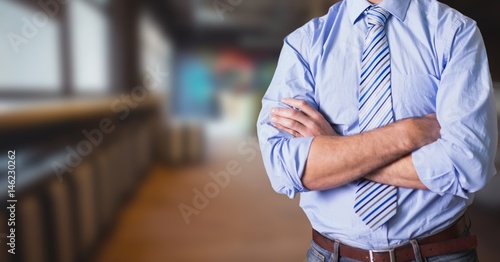 Midsection of businessman with arms crossed standing In office photo