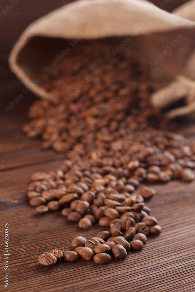 Coffee is poured from a burlap on a wooden background Coffee is poured from a burlap on a wooden background