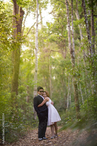 A couple in formal dress black suit and white dress romance in the pine forest before wedding, Thailand