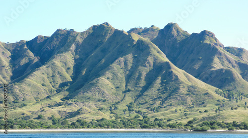 Coastline of mountains with green vegetation and blue ocean water at Labuan Bajo in Flores, Indonesia.