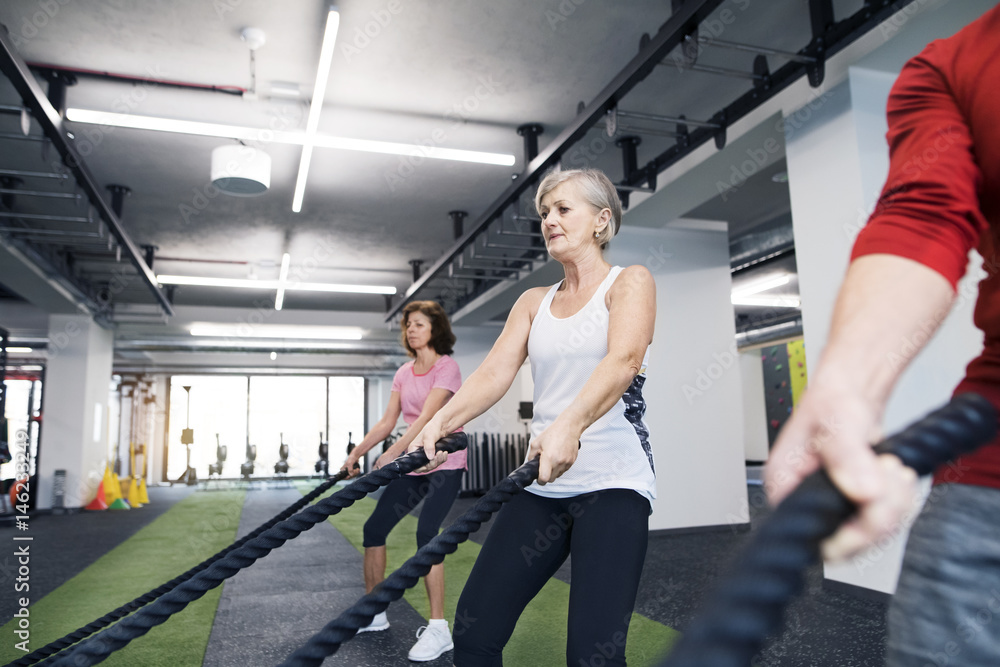 Seniors in gym working out with battle ropes Seniors in gym working out with battle ropes
