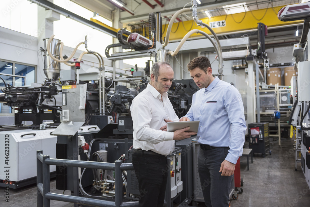 Two men with tablet talking in factory shop floor Two men with tablet talking in factory shop floor