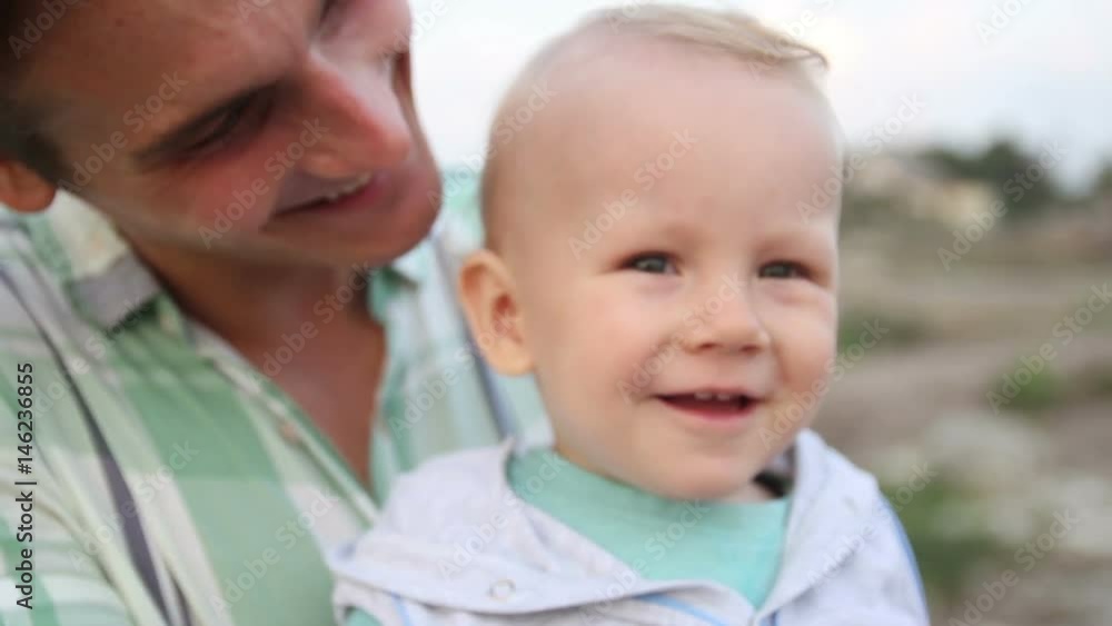 Little happy boy is siting on his fathers arm Little happy boy is siting on his fathers arm