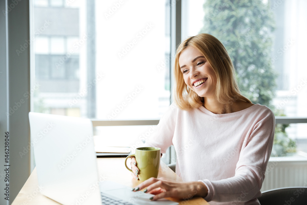 Happy lady sitting in office coworking while using laptop computer Happy lady sitting in office coworking while using laptop computer
