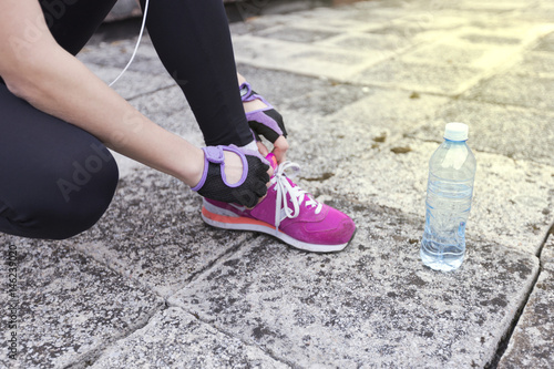 Female young fit runner tying her shoelaces.