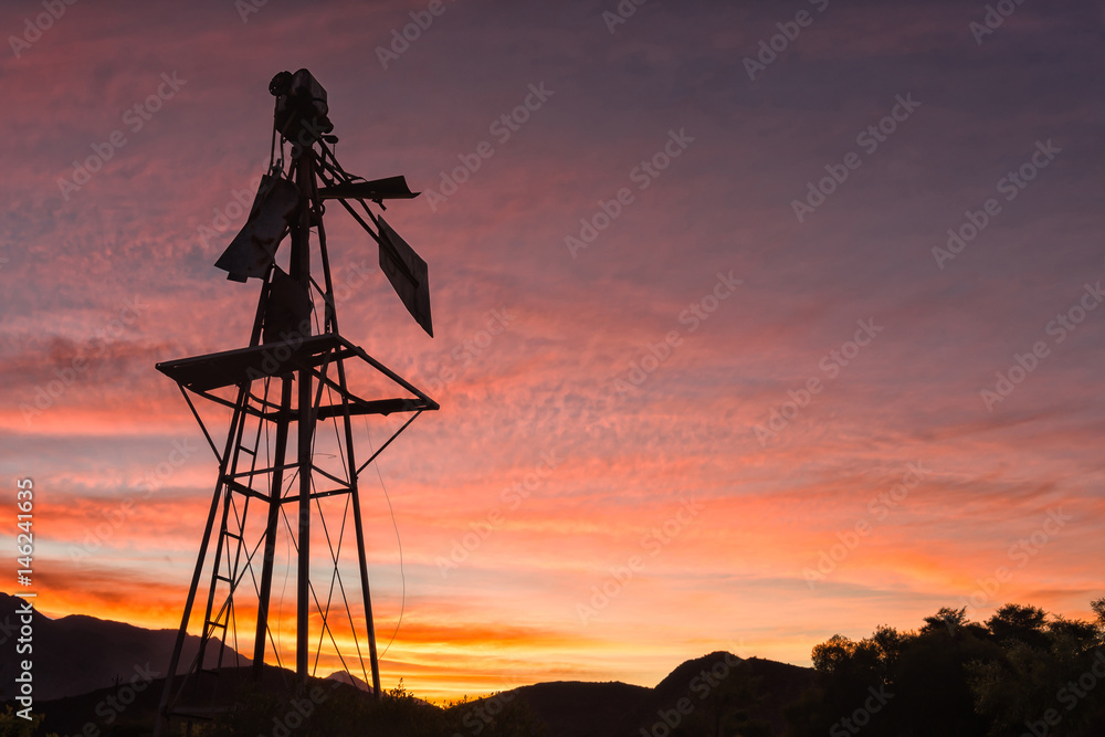 Silhouette of a broken windmill against sunset