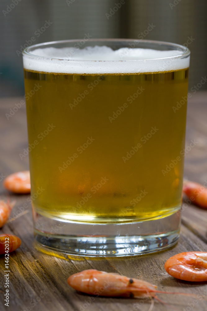 Glass of fresh cold beer on wooden surface with boiled shrimps Glass of fresh cold beer on wooden surface with boiled shrimps