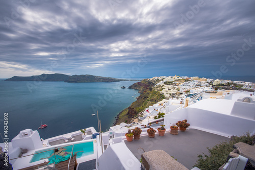 Oia town on Santorini island  Greece. Traditional and famous houses  churches with blue domes over the Caldera  swimming pool   jacuzzi  Aegean sea