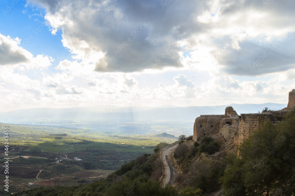 Ancient knights fortress and amazing Upper Galilee mountains view, North Israel. Evening shot. Big grey rain clouds. Sunlight rays and shadows on the hills.