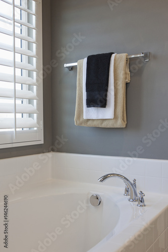 Towel rail and bathtub by window in domestic bathroom photo