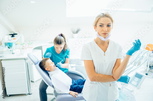 Dentist looking concerned in surgical mask standing with arms crossed at dental clinic