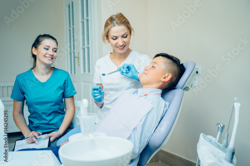 Femaleale dentist  her assistant and handsome patient in dental practice.