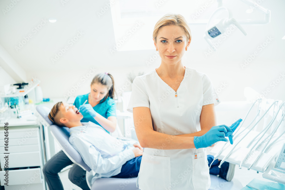 Obraz premium A portrait of a dentist with his team working in the background