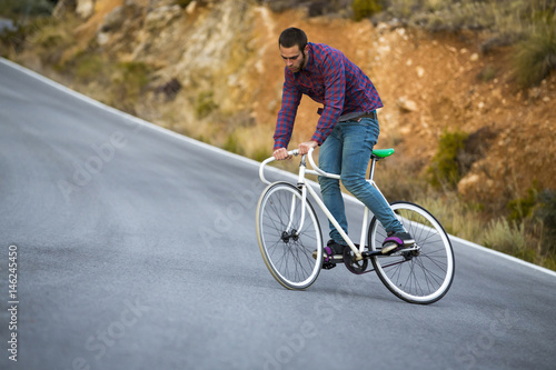 Cyclist man riding fixed gear sport bike in sunny day on a mountain road © juananbarros