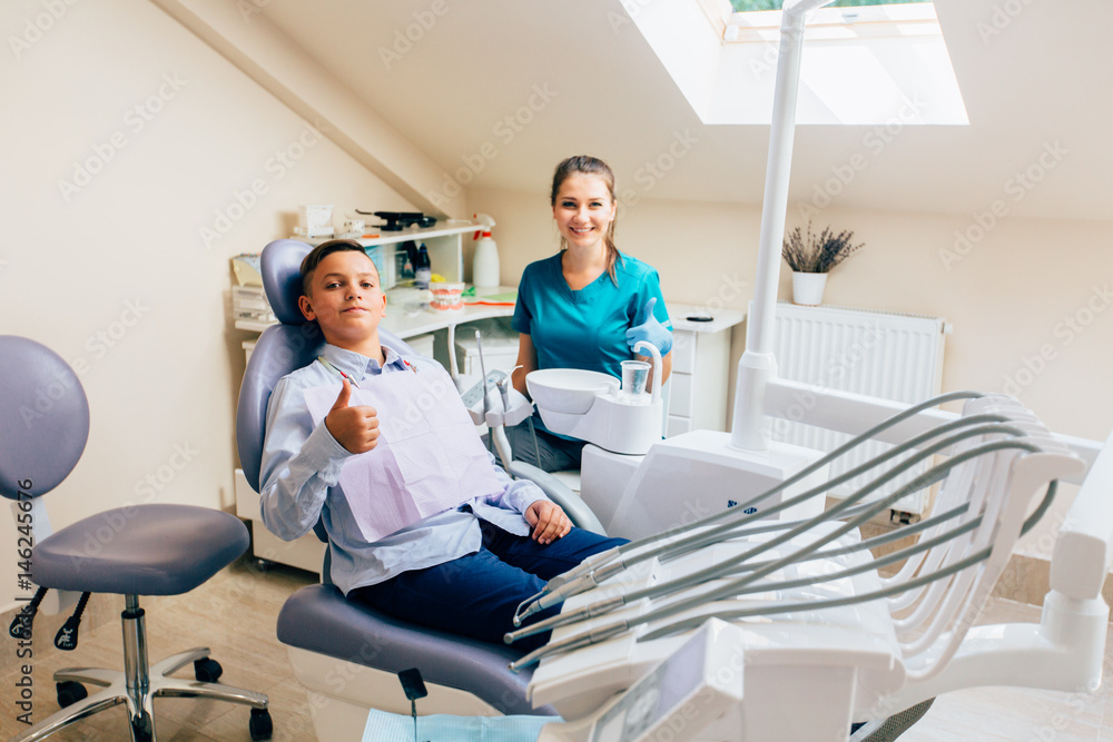 Fototapeta premium Handsome teenager boy giving thumbs up at dentist office