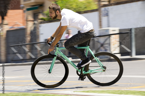 Cyclist man riding fixed gear sport bike in sunny day on a city